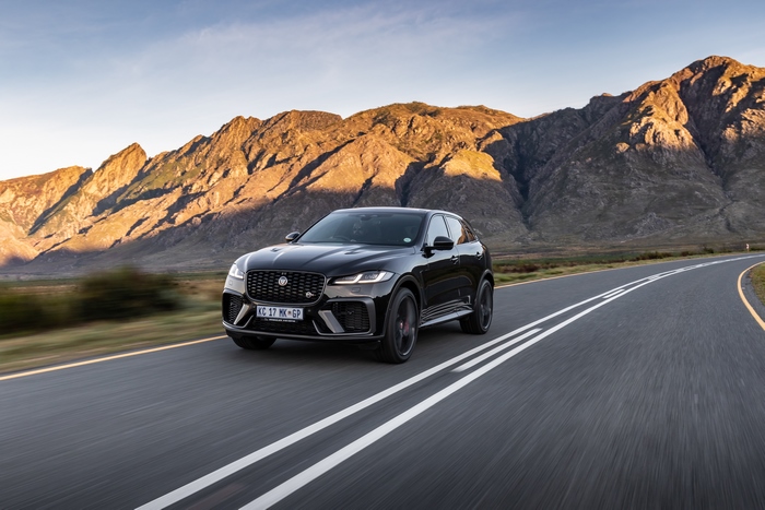 Black Jaguar F-Pace SVR SUV on mountain road at sunset.