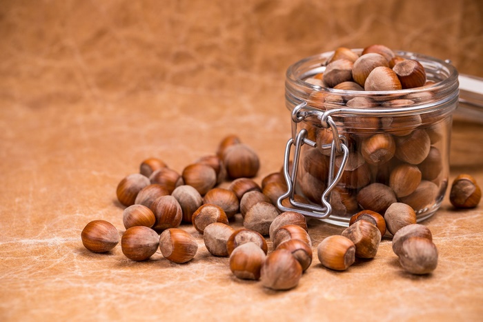 Hazelnuts in a glass jar with some spilled out