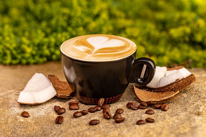 Coconut coffee with heart latte art in black cup