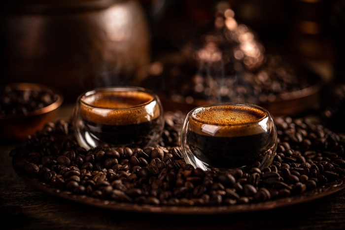 Steaming coffee cups and roasted coffee beans