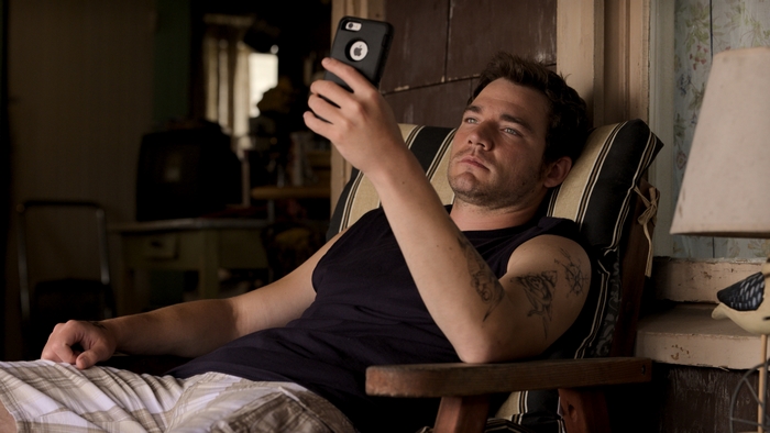 Daniel Durant looking at his iPhone in a chair