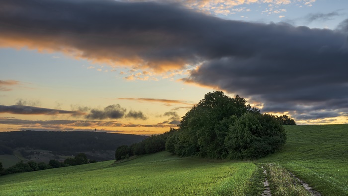 Dramatic Sunset over Green Fields and Hills