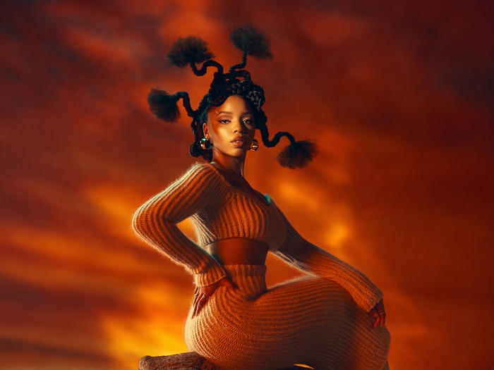 Chloe Bailey in orange knit set with elaborate hairstyle