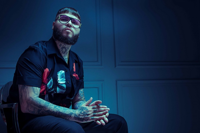 Farruko posing dramatically in blue light