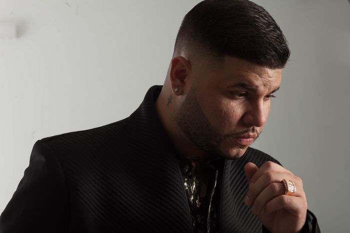 Farruko in black jacket, looking down