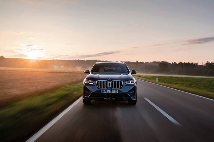 BMW Alpina XD4 SUV driving into the sunrise