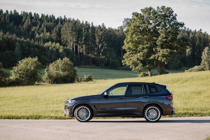 BMW Alpina XD3 SUV parked by a green field and forest