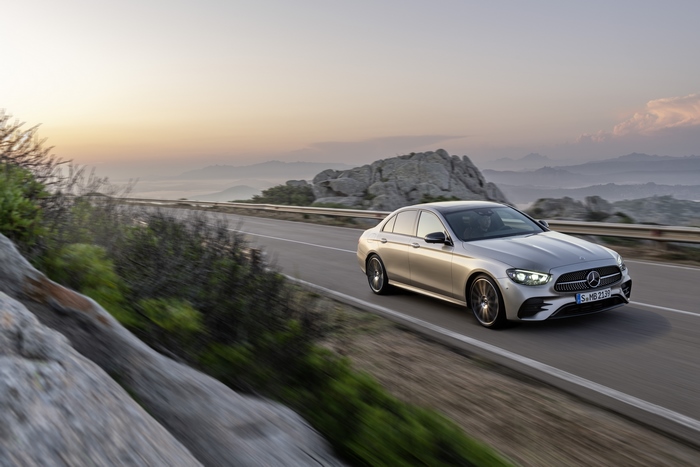 Silver Mercedes-Benz E 450 driving on mountain road at sunset