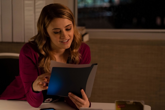 Josephine Langford smiling while reading documents in After We Fell