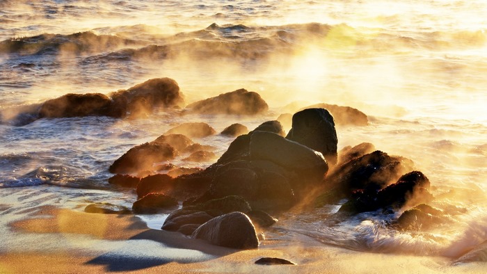Sea smoke and golden light on coastal rocks