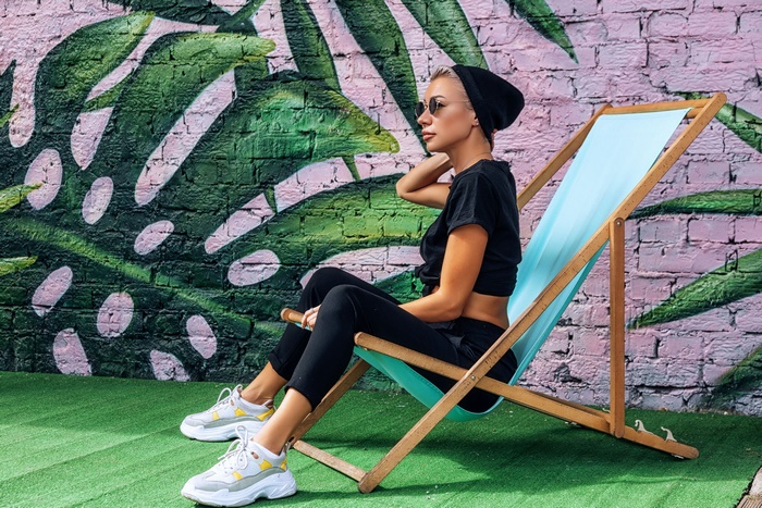 Model in deck chair with tropical leaf graffiti