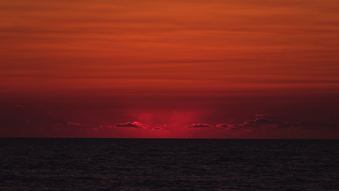 Fiery Red Sunset Sky Over Dark Ocean