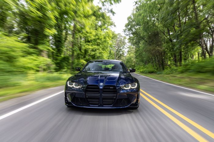Blue BMW M3 Competition driving with motion blur on road