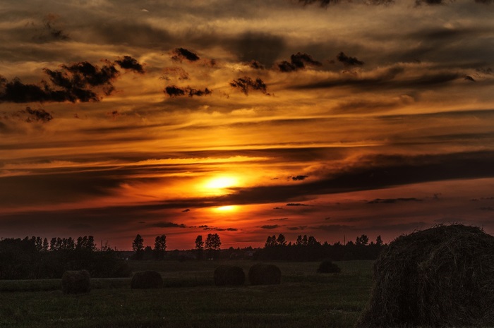 Dramatic Sunset Sky over Field with Hay Bales