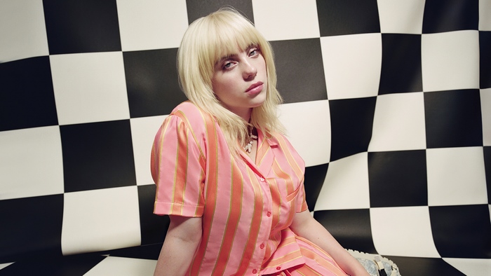 Billie Eilish in pink striped shirt against checkered background