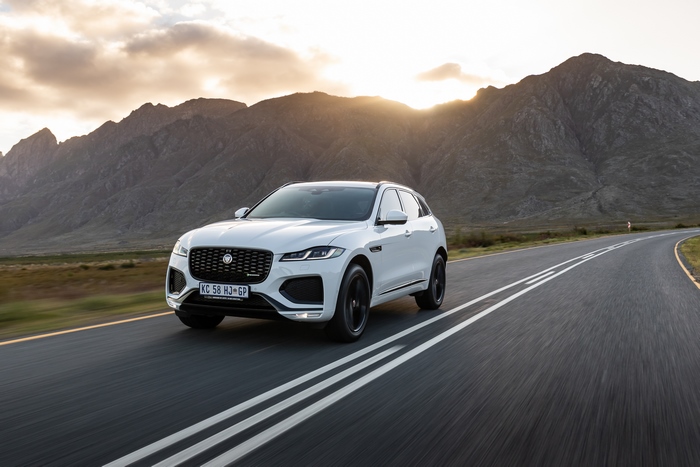 White Jaguar F-Pace SUV on a mountain road at sunset