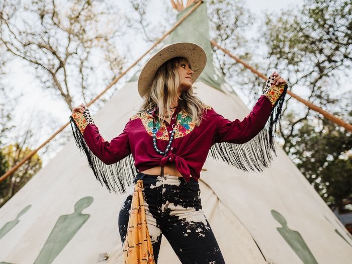 Lainey Wilson in a fringed shirt and cowboy hat