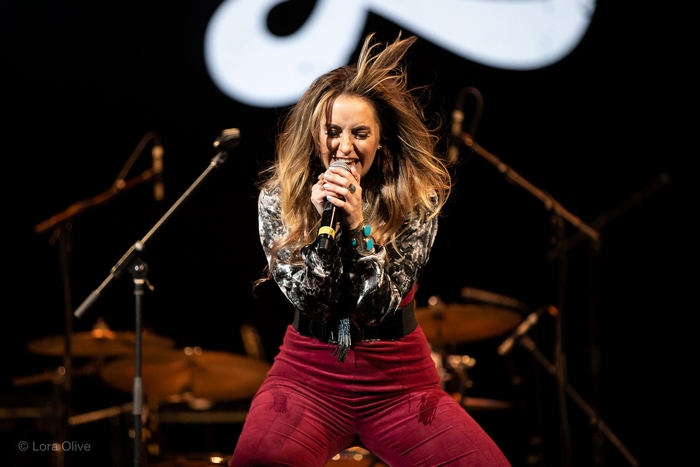 Lainey Wilson singing with intensity on stage