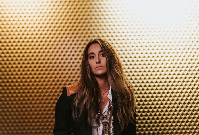 Lainey Wilson in black jacket against golden acoustic foam