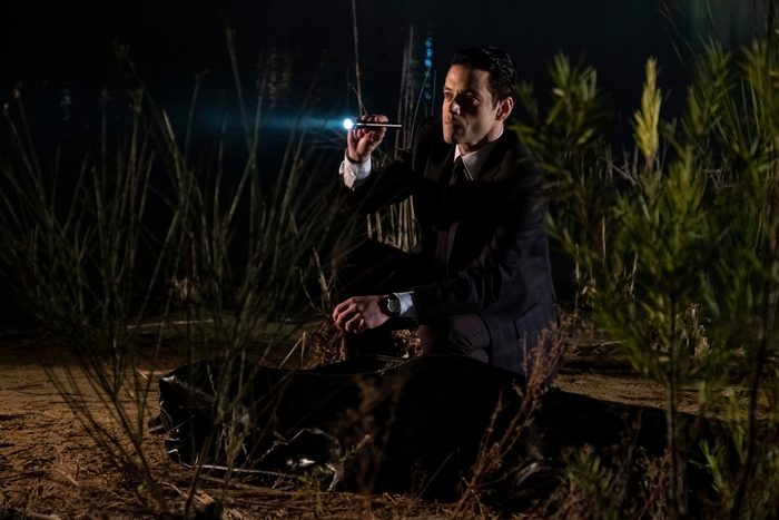 Rami Malek investigating a dark scene with a flashlight