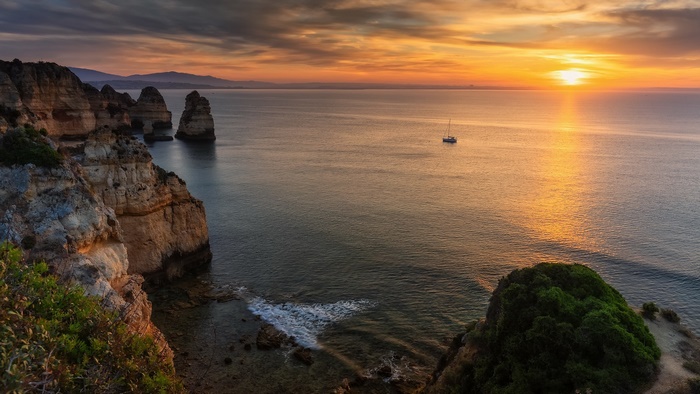 Golden hour at a rugged coastline with a lone boat