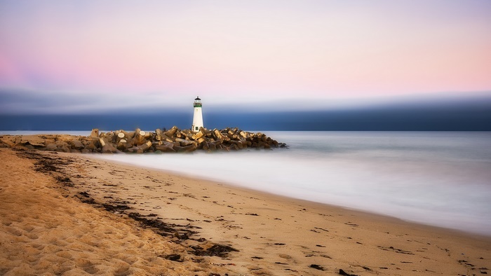 Lighthouse on a rocky breakwater at sunset