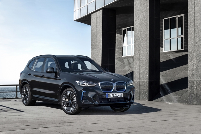 Black BMW iX3 M Sport electric SUV by modern building