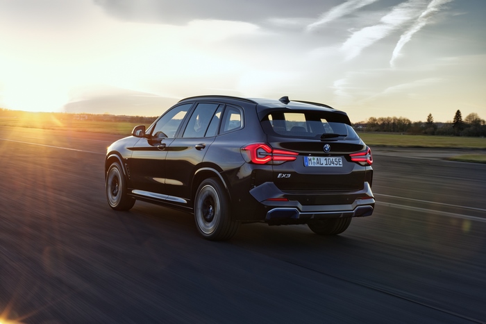 Black BMW iX3 M Sport electric SUV driving at sunset