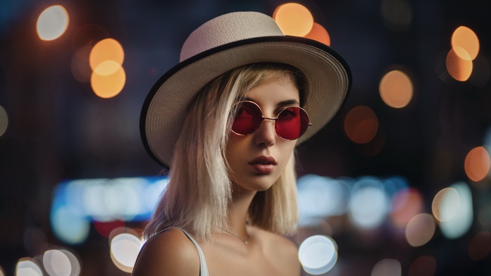 Blonde model in hat and red sunglasses with bokeh lights