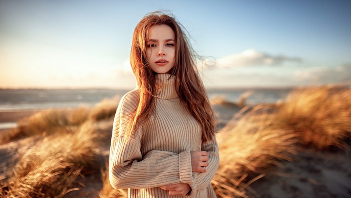 Redhead model on beach in sweater with blurred background