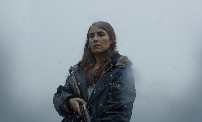 Noomi Rapace with a rifle in falling snow