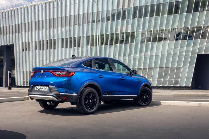 Blue Renault Arkana "Pulse" SUV parked by modern building