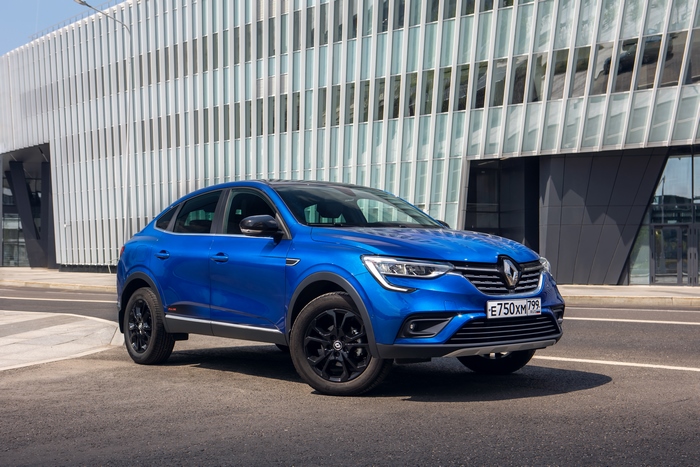 Blue Renault Arkana SUV in front of a modern building