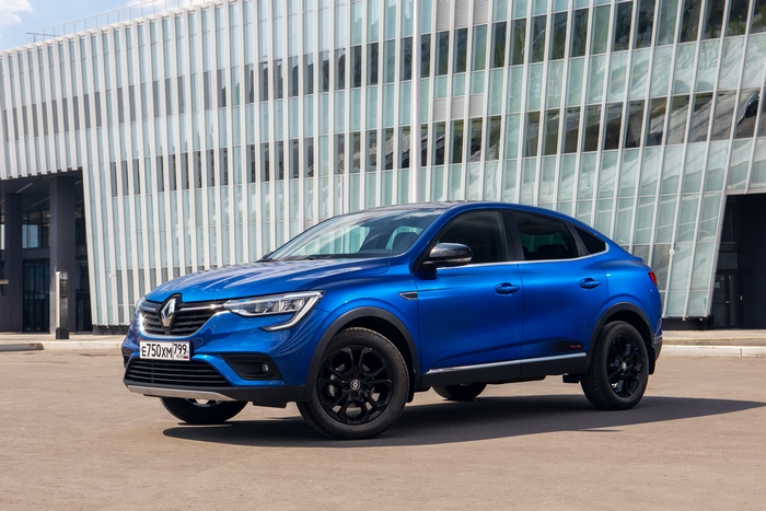 Blue Renault Arkana Pulse SUV in front of modern building