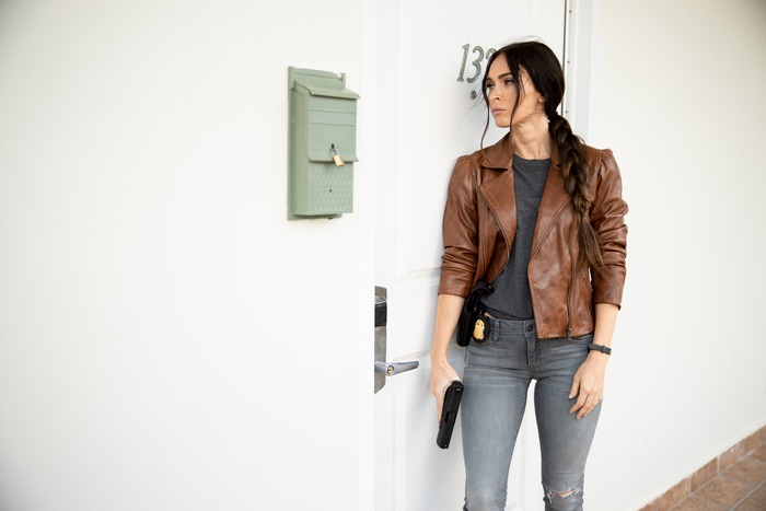 Megan Fox holding a gun in a leather jacket