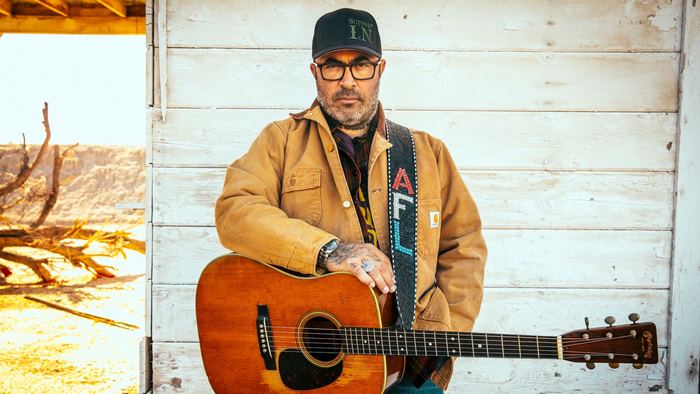 Aaron Lewis in brown jacket holding acoustic guitar