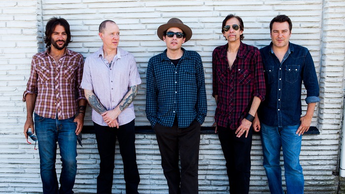 The Wallflowers band posing in front of a brick wall