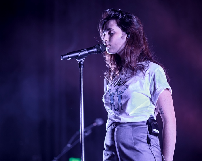 Clairo singing into microphone on stage