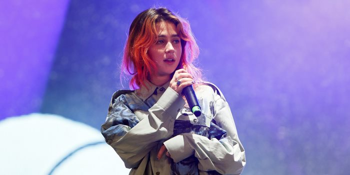Clairo performing live on stage with microphone