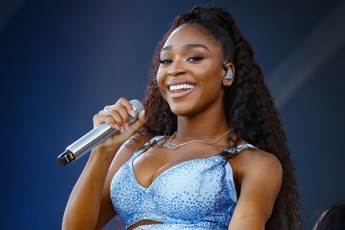 Normani smiling and singing on stage