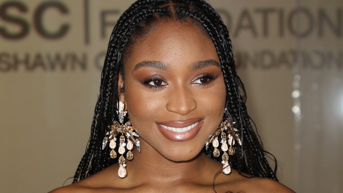 Normani smiling with braided hair and large earrings