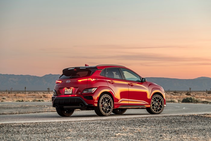 Red Hyundai Kona N SUV on desert road at sunset