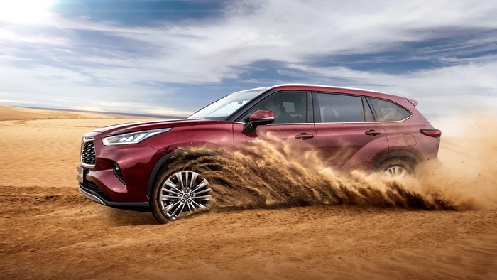 Dynamic Toyota Highlander Hybrid SUV driving through desert sand
