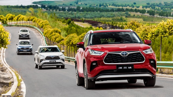 Red Toyota Highlander Hybrid leads SUVs on winding road