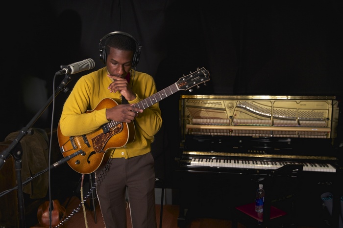 Leon Bridges playing guitar in studio with piano