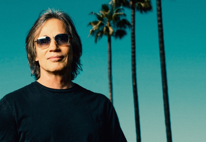Jackson Browne smiling in sunglasses with palm trees