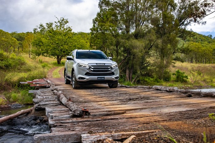 Isuzu MU-X SUV crossing a rustic wooden bridge