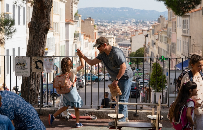 Man and girl high-fiving in city with mountain view