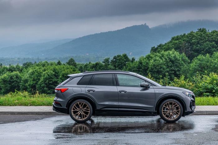 Audi Q4 e-tron SUV on wet road with mountains