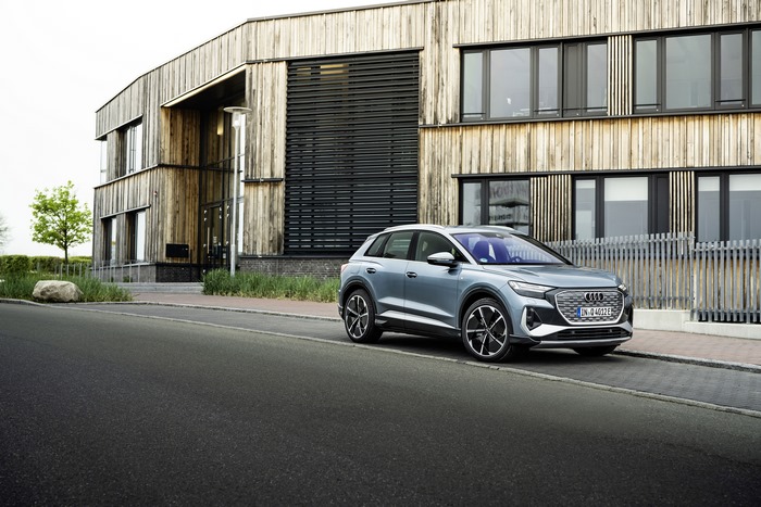 Audi Q4 e-tron SUV by modern wooden building